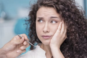 Young beautiful woman suffering from toothache in consulting room