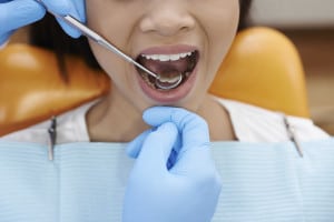 Dentist using mouth mirror to observe back of front teeth